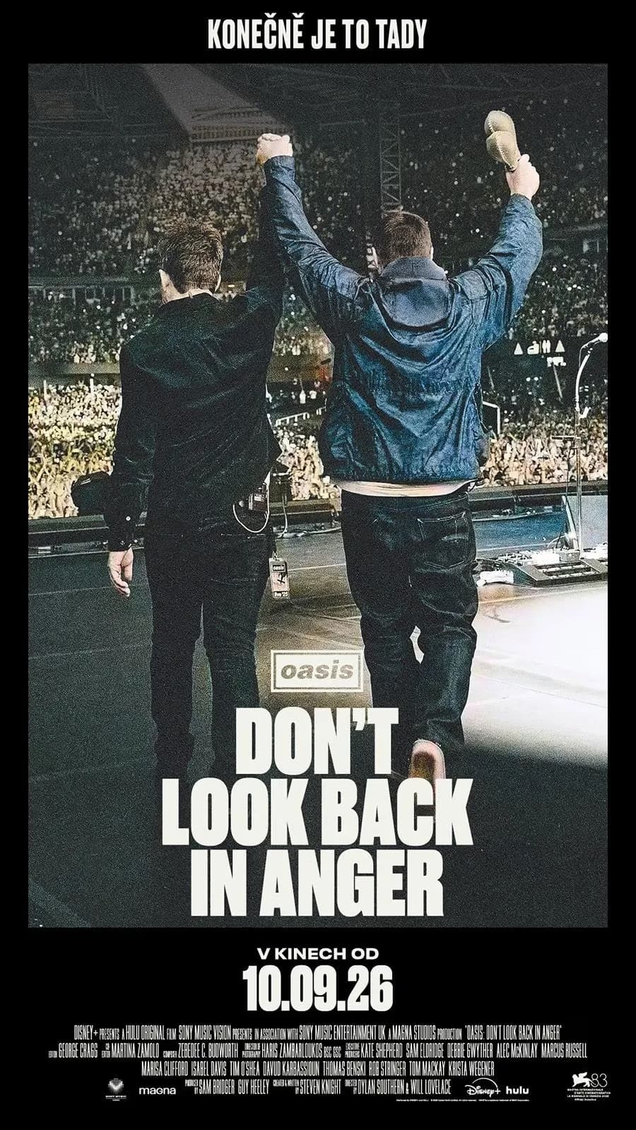 Dwaj mężczyźni na scenie stadionu patrzą na tłum, poniżej tytuł Don't Look Back In Anger.