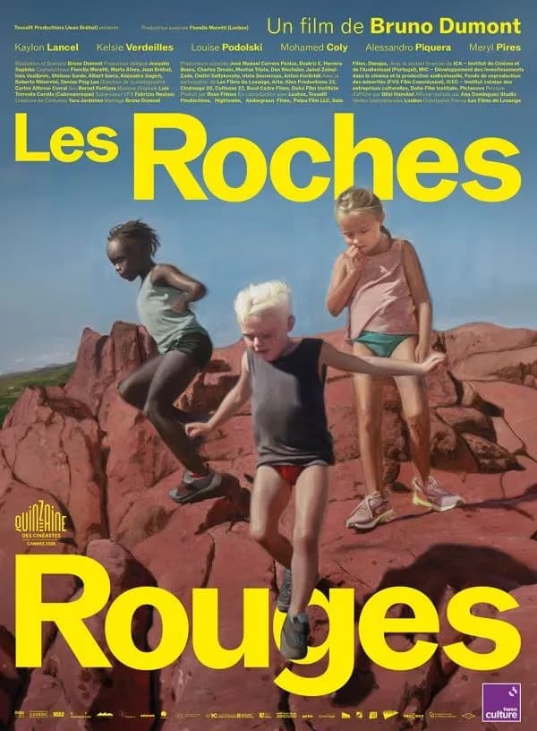 Three children jumping and playing on jagged red rocks under a clear blue sky.