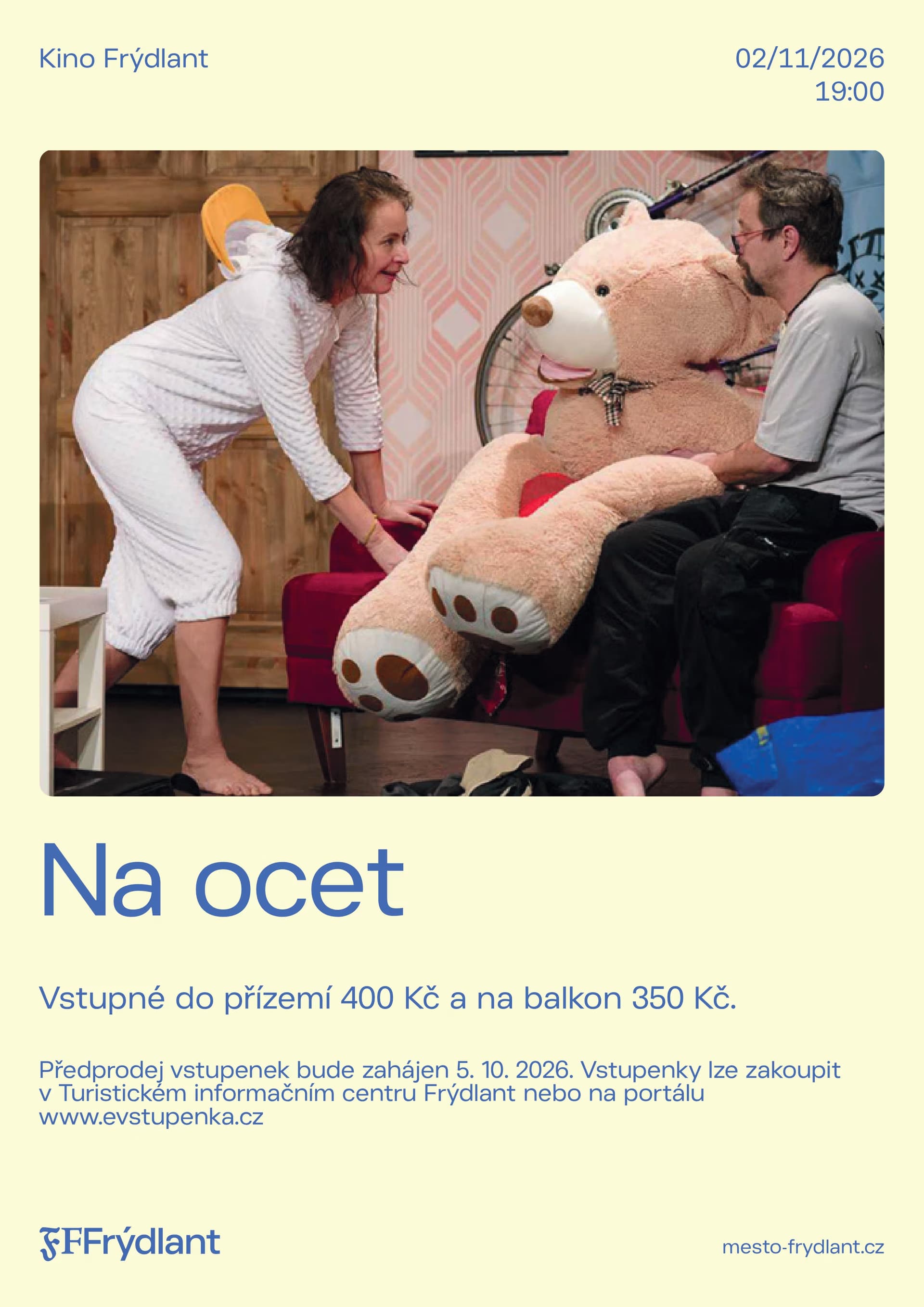 Dwoje aktorów odgrywa scenę z wielkim pluszowym misiem na kanapie.