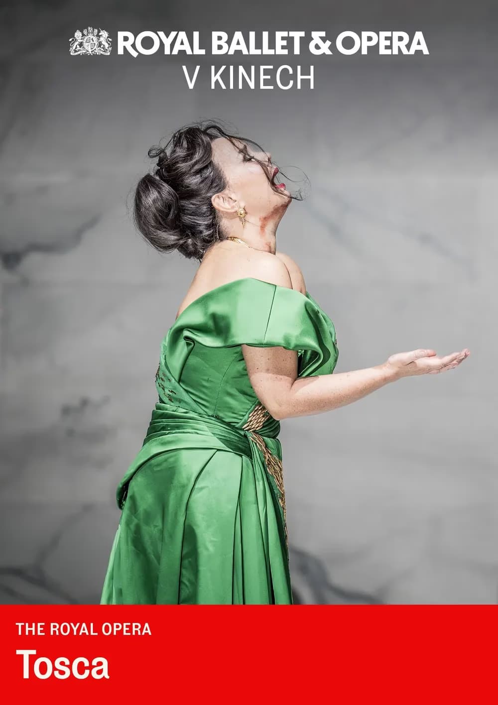 An opera singer in a green dress performs dramatically against a grey background.