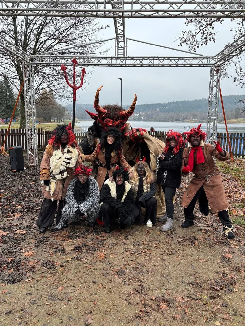 Gruppe von Menschen in Krampus-Kostümen posiert im Freien an einem See.