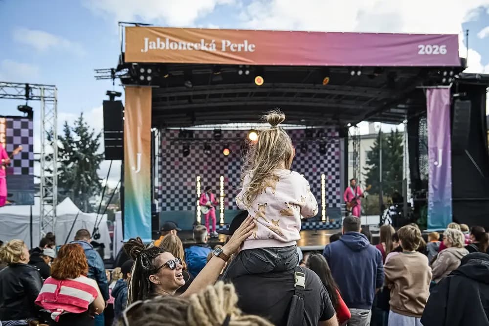 Dziecko siedzi na ramionach dorosłego podczas festiwalu muzycznego przed sceną.