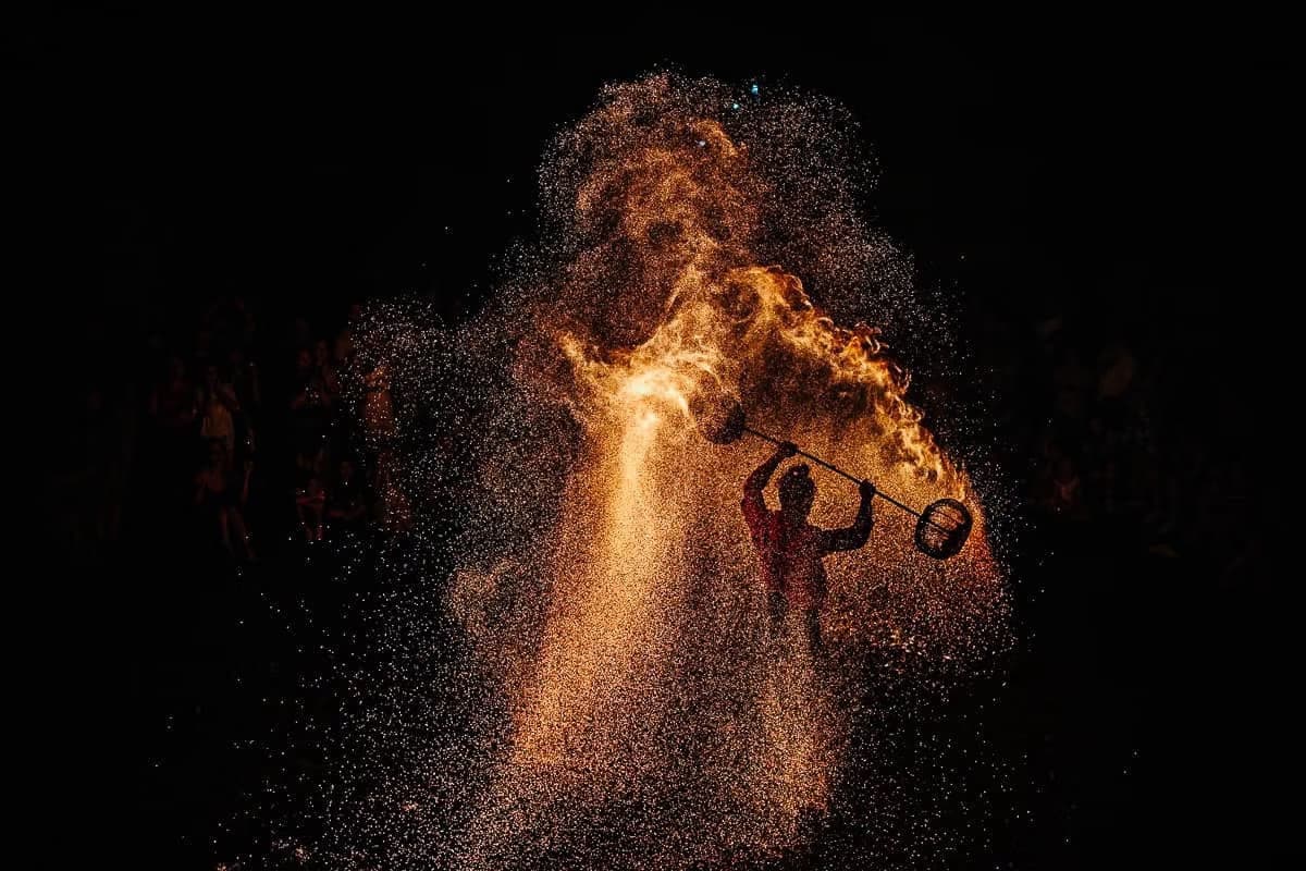 Die Silhouette einer Person schwingt nachts Feuer-Poi und erzeugt einen hellen Funkenregen.