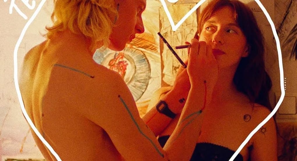 A man paints on a woman's face, both framed by a large hand-drawn heart outline.