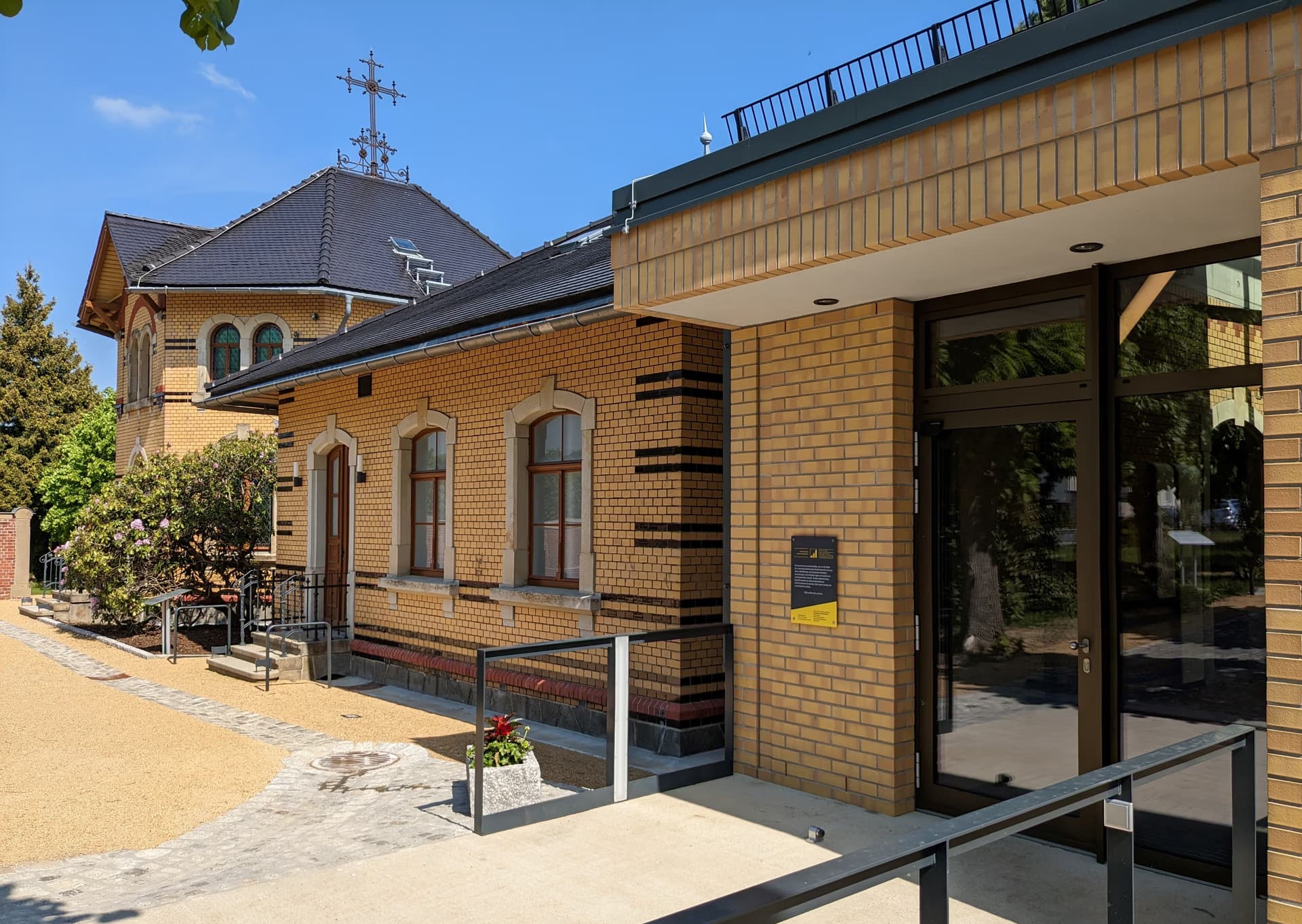 Modern entrance to a historic yellow brick building under a clear blue sky.