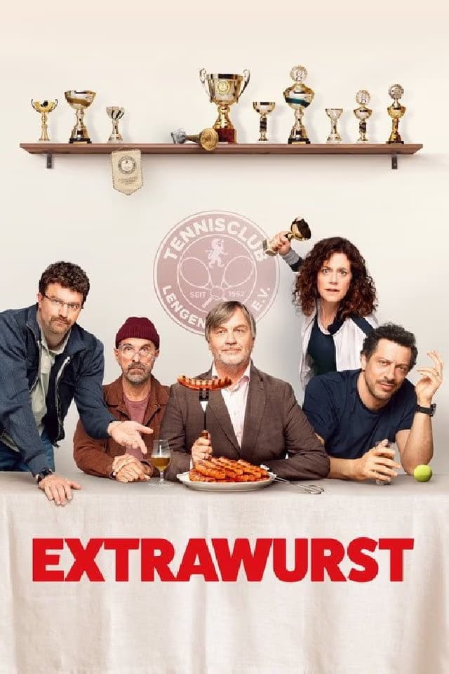 Five people pose behind a table featuring a sausage dish and trophies on the wall behind.