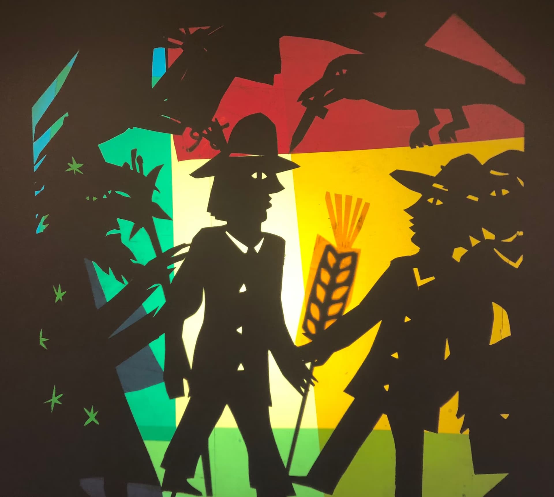 A colorful paper-cut illustration depicts silhouettes of figures with hats and a wheat stalk against abstract shapes.
