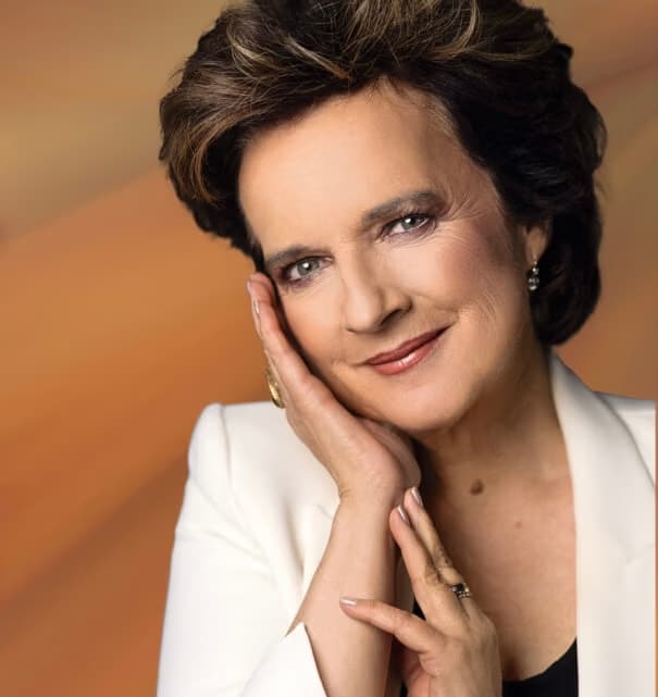 A close-up portrait of a woman with dark hair wearing a white jacket.