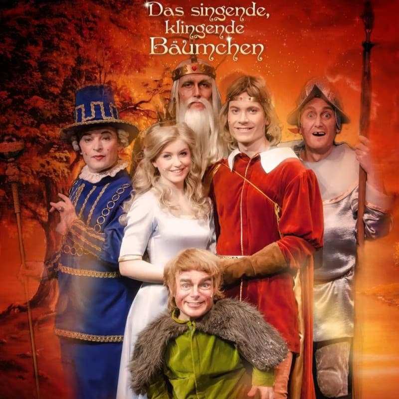 Pět herců v pohádkových kostýmech pózuje na oranžovém pozadí pod titulkem filmu.