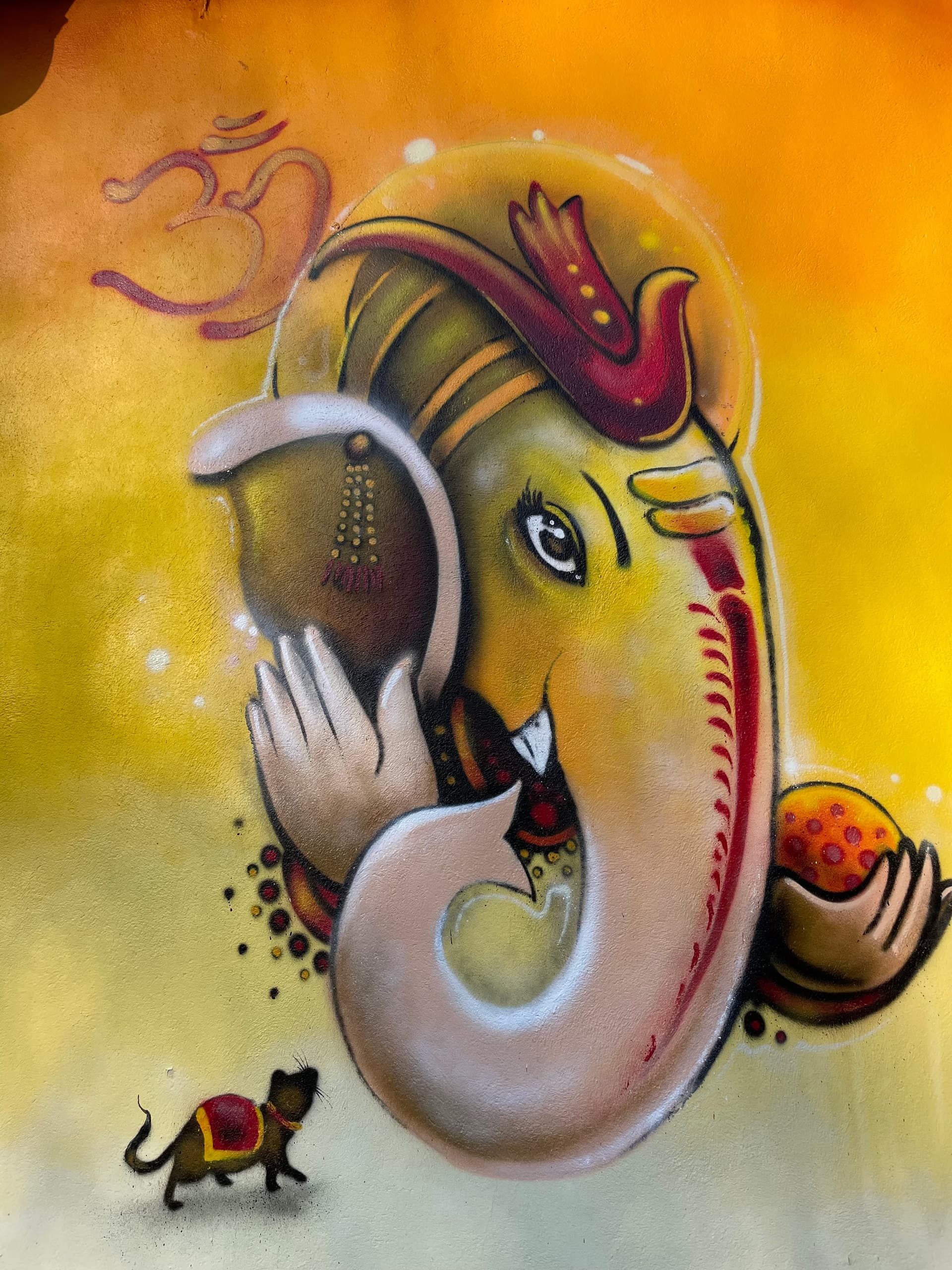 A painting of Lord Ganesha with a small mouse on a yellow background.