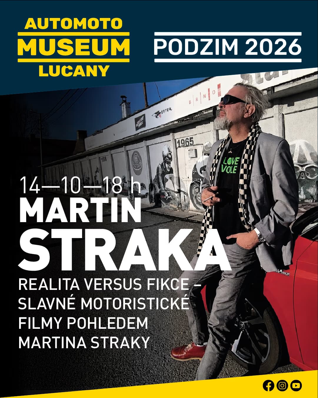 Muž v obleku stojí u červeného auta před budovou Automoto muzea v Lučanech.