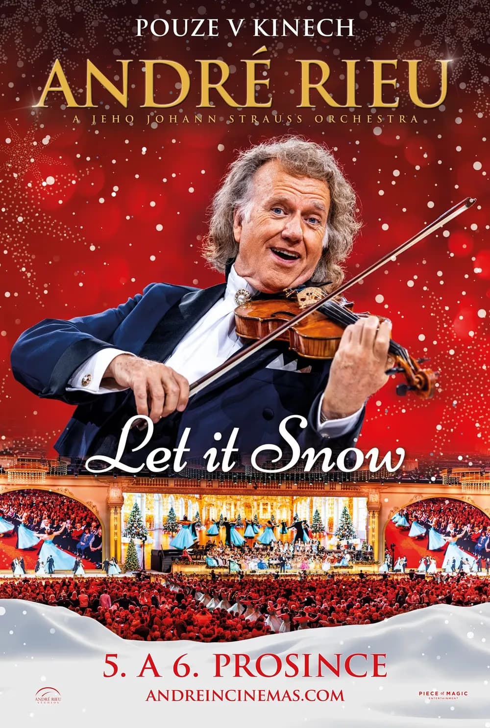 Andre Rieu smiles while playing violin in front of a red Christmas-themed stage background.