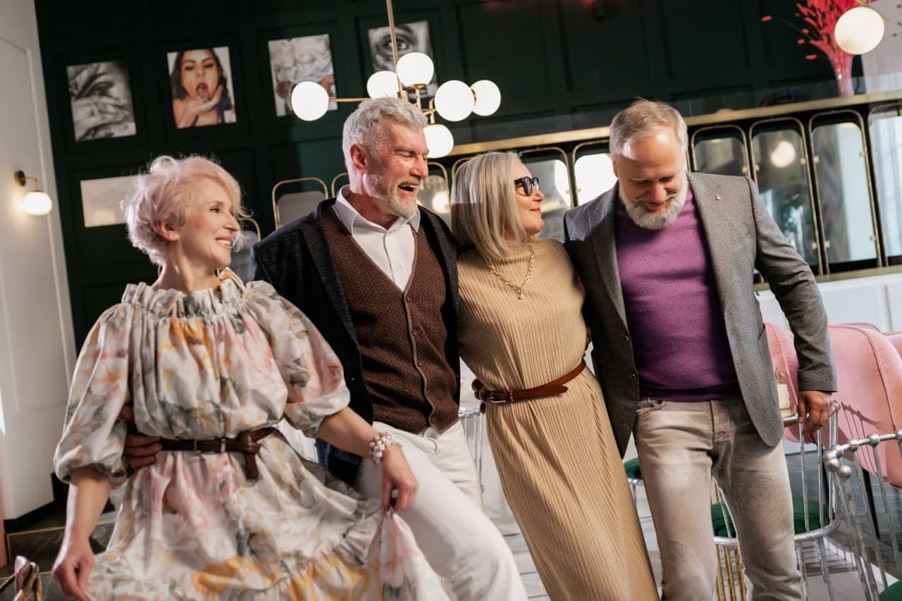 Four smiling middle-aged friends posing together in a stylish restaurant setting.