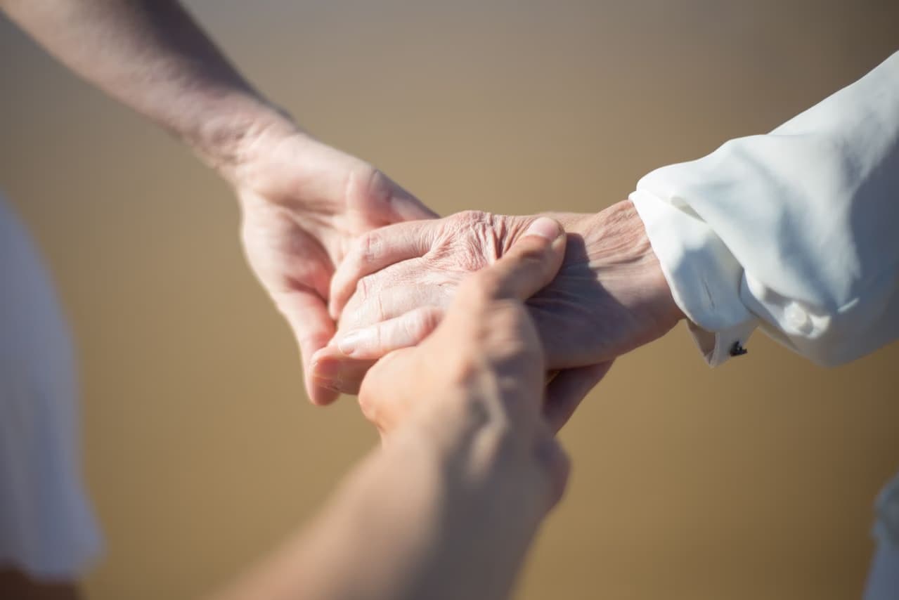 Close-up of hands gently holding each other against a soft blurred background.