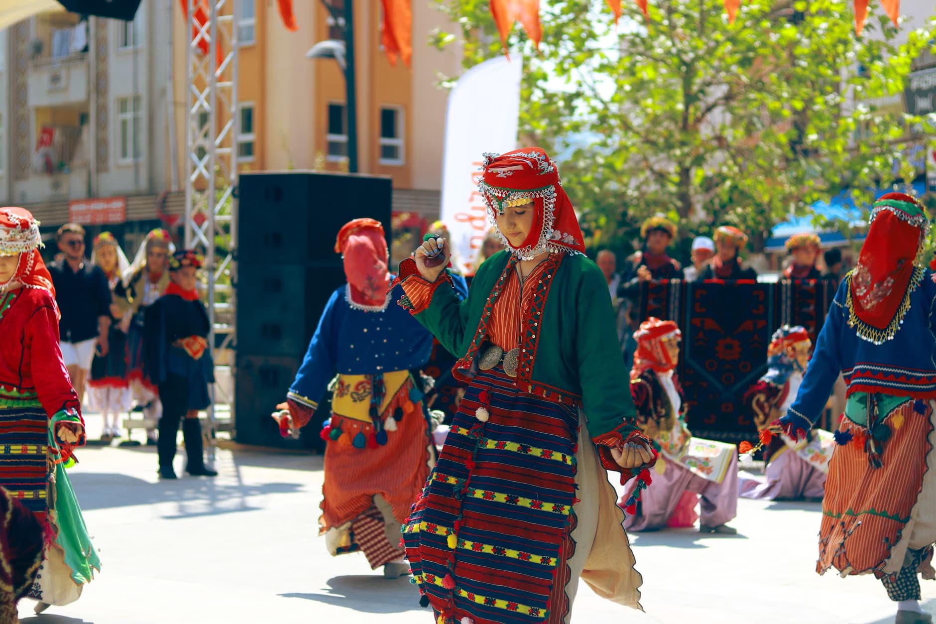 People in traditional vibrant folk costumes dance outdoors during a festive cultural celebration.