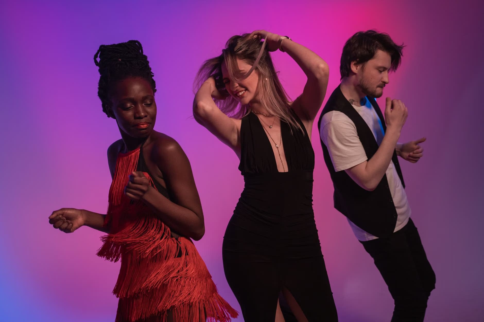Three young people dance joyfully against a vibrant purple and pink gradient background.