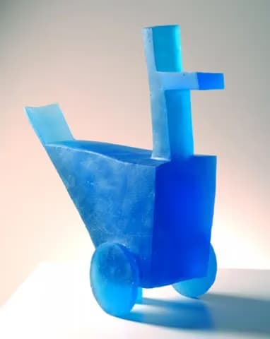 A blue abstract sculpture of a duck on wheels stands against a plain background.
