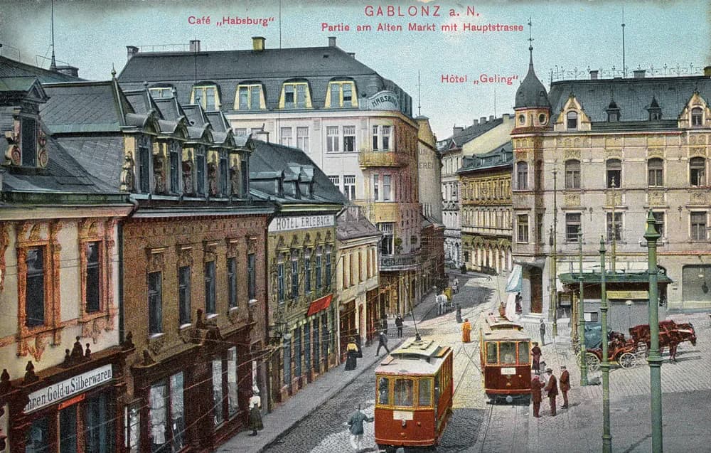 Historic postcard view of Gablonz street scene featuring tram cars and old buildings.
