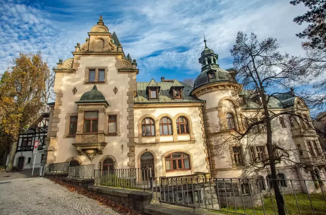 Zdobiona zabytkowa willa z wieżami i detalami architektonicznymi stoi pod błękitnym niebem.