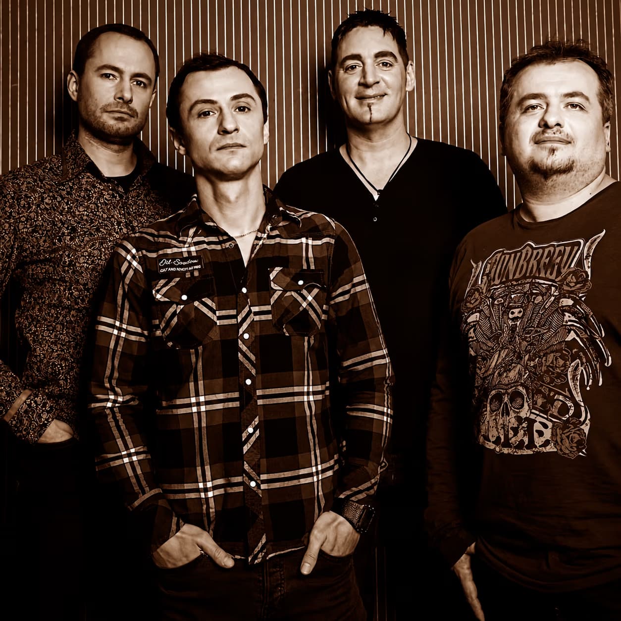 Four men standing together in a row against a vertically striped textured background.