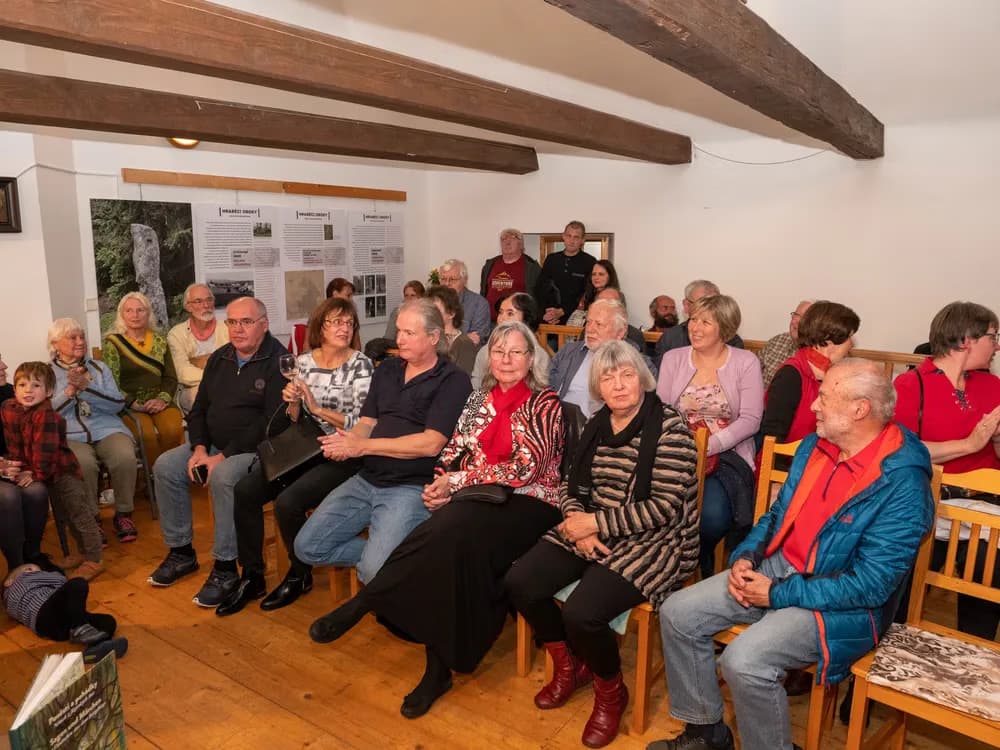 A diverse group of people sits in chairs listening during an indoor presentation event.