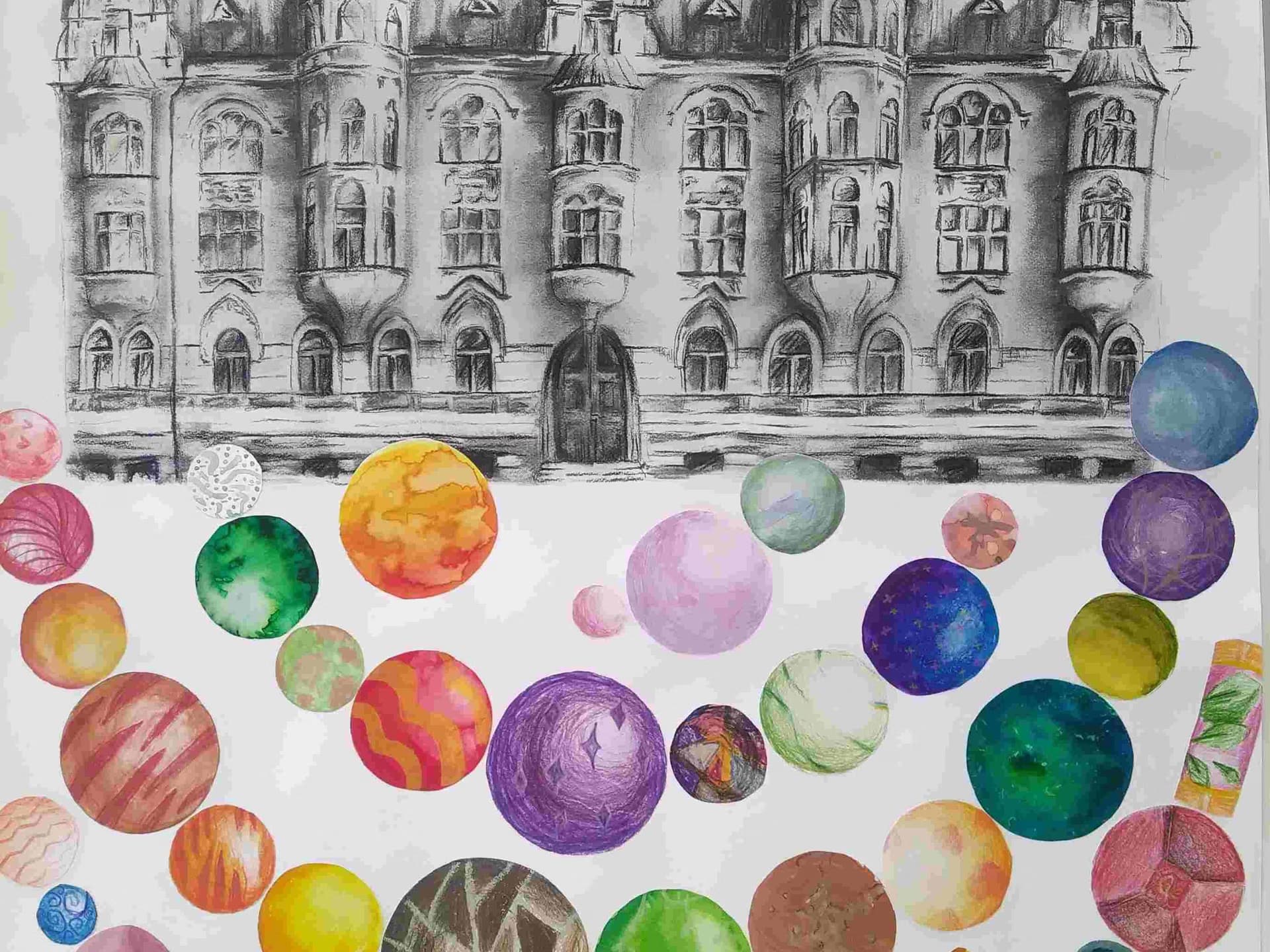 A graphite drawing of an old castle sits above many colorful painted spheres.