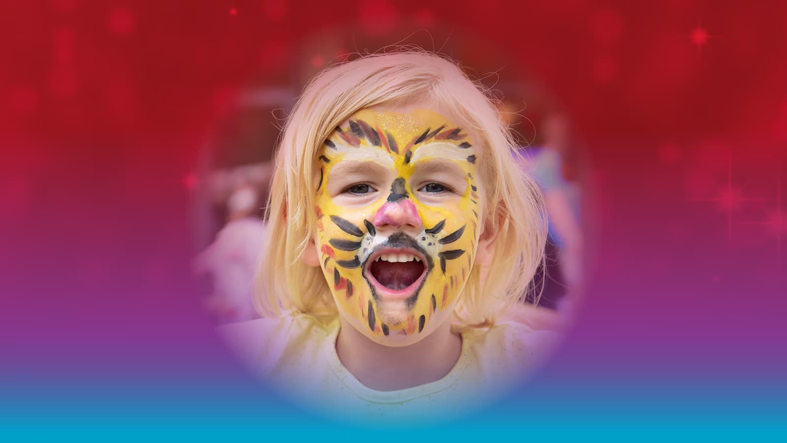 A child with tiger face paint smiles with mouth open against a blurred background.