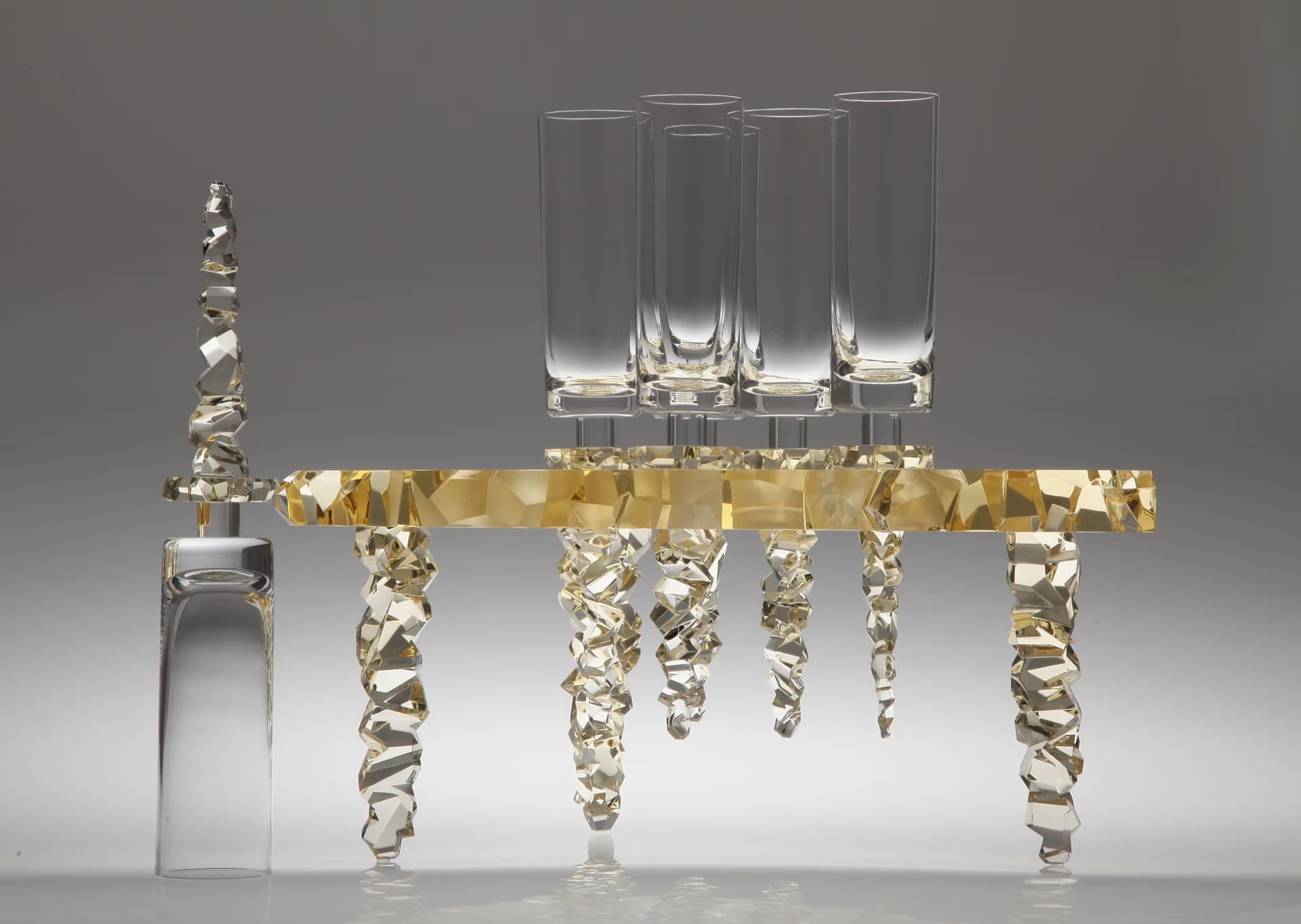 Eine kunstvolle Kristallskulptur zeigt hohe Glaszylinder auf einem zerklüfteten, goldenen Kristallgrund.