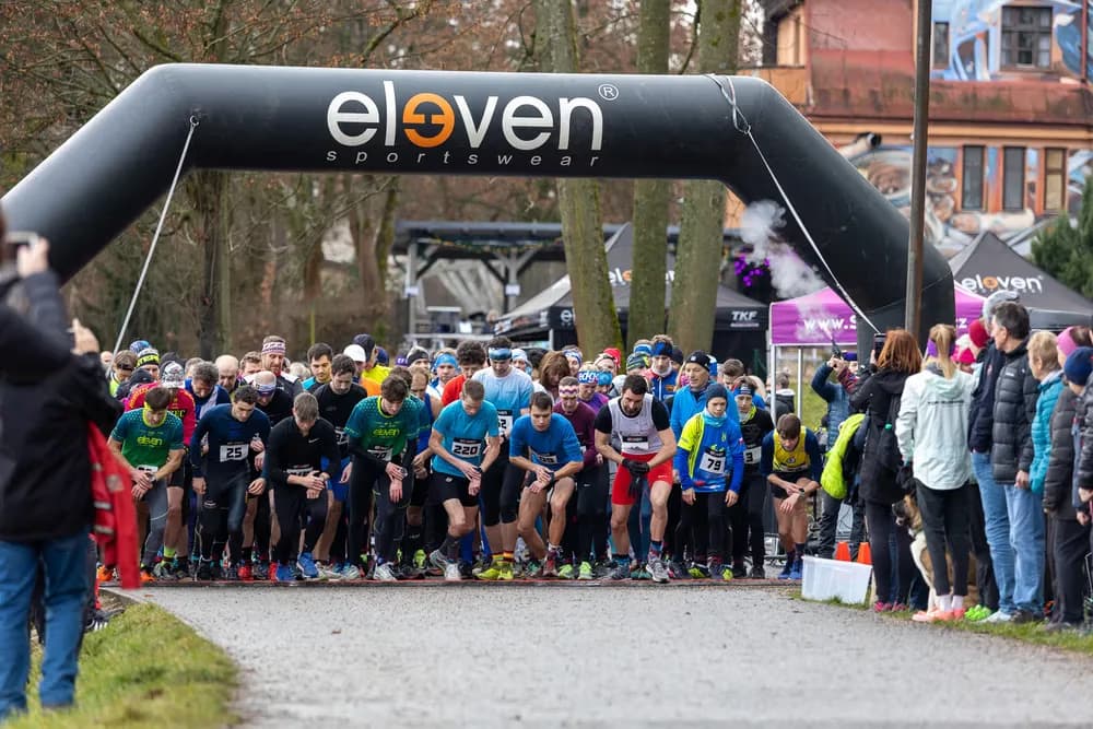A large group of runners at the starting line under an inflatable eleven sportswear arch.
