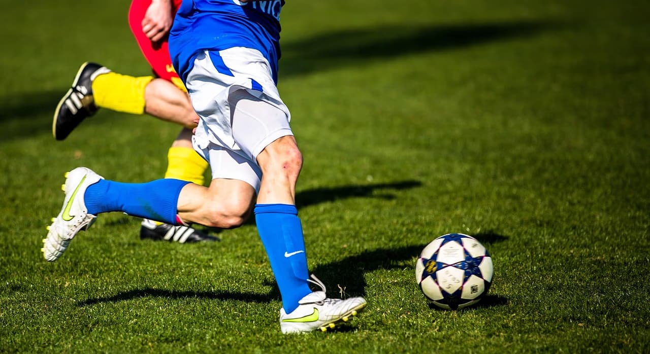 Soccer players in action, one dribbling a ball on a grassy field.