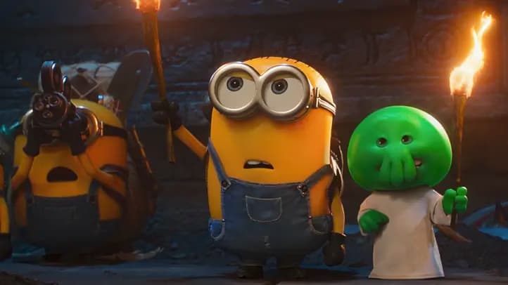 Minions and a green alien character hold flaming torches inside a dark cavernous setting.