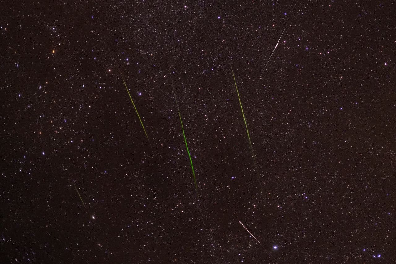 Multiple bright meteor streaks cutting across a dark, star-filled night sky.