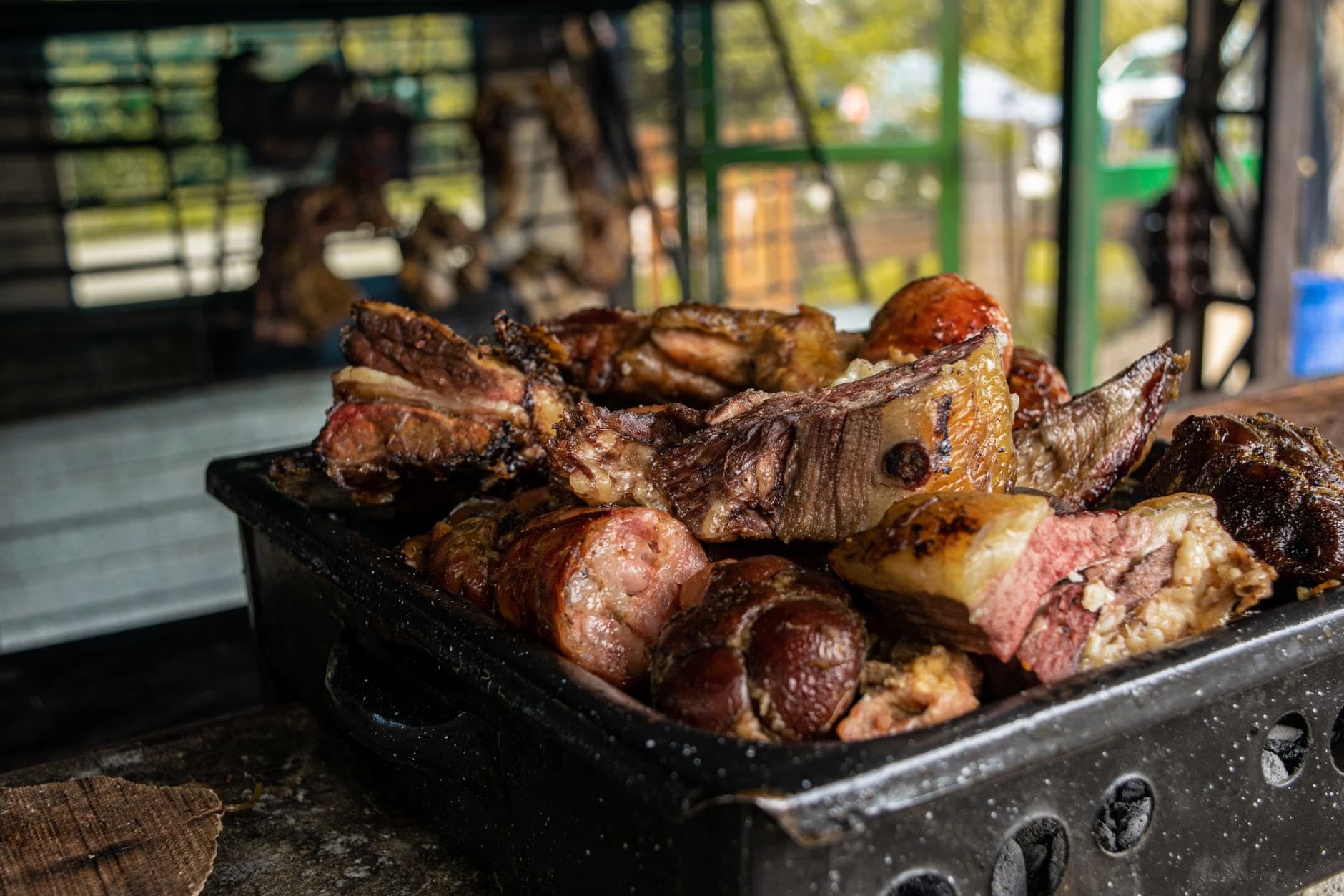 Kawałki pieczonego mięsa są ułożone w czarnej metalowej brytfannie na grillu na zewnątrz.