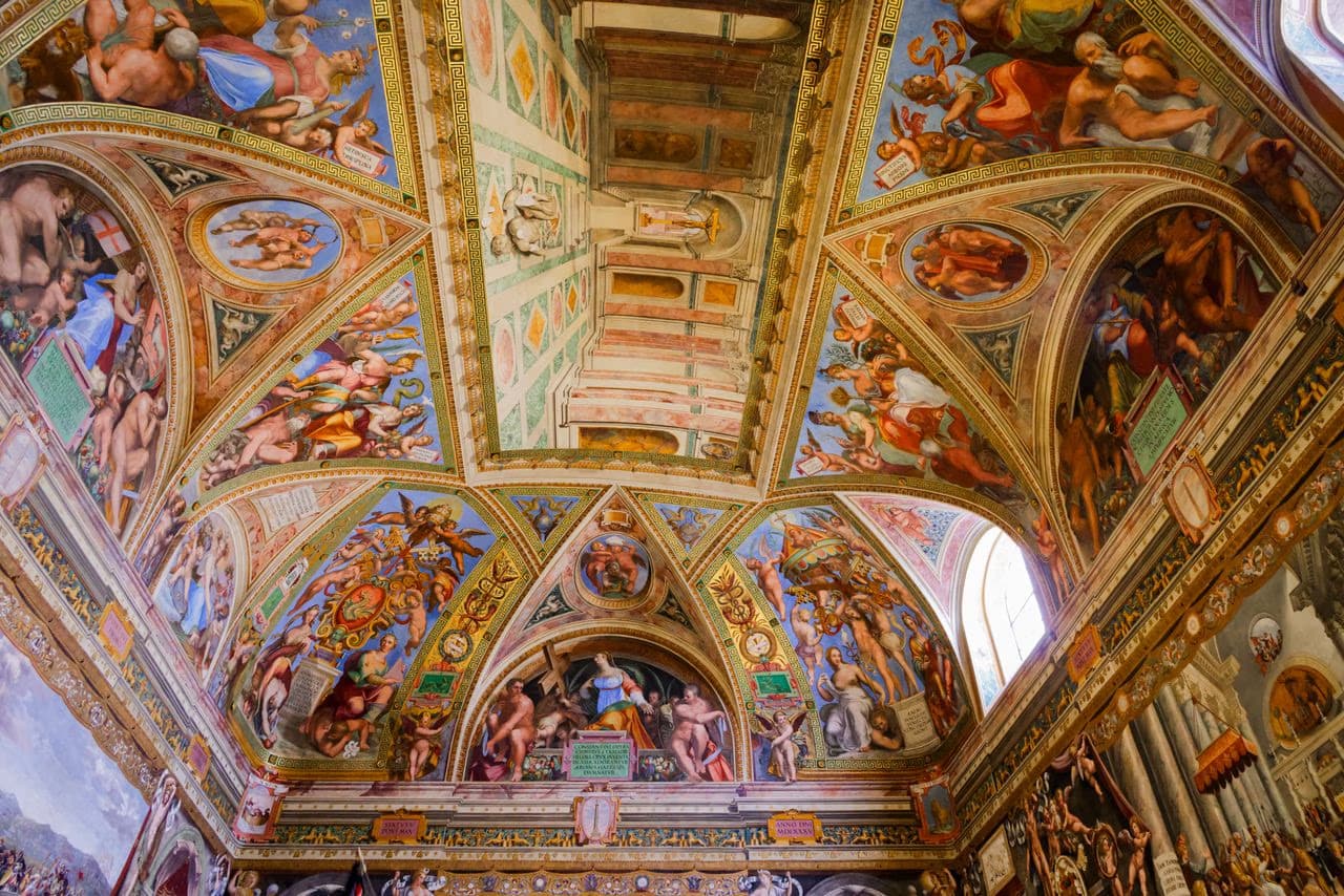 Elaborate Renaissance ceiling frescoes decorate the vaulted interior of a historic European cathedral.